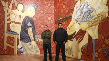 Cosijosea Cernas (à gauche) et Dario Canul (à droite) devant l’une de leurs peintures murales (originellement exposées à Los Angeles) ici au musée de l’hospice Comtesse de Lille.